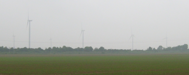 4 wind turbines in the misty distance on flat french farmland